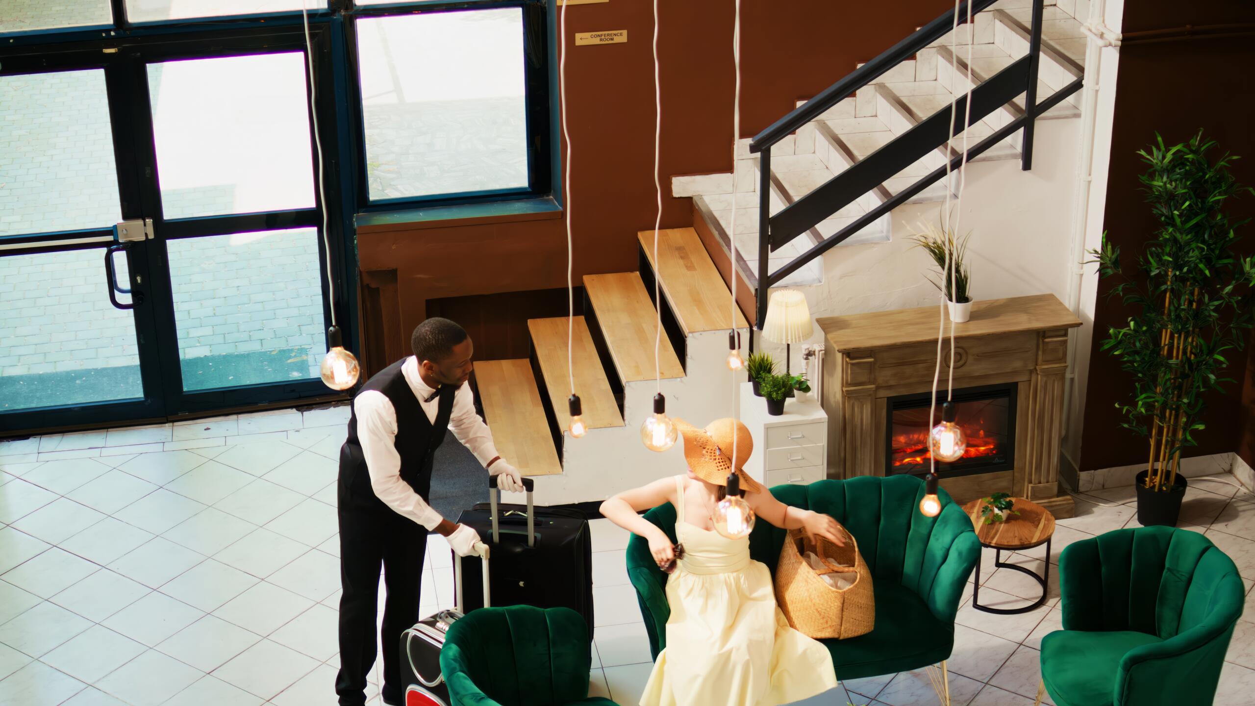 Hotel concierge carrying baggage for tourist, helping with trolley bags in reception lobby. Bellboy working in luxury tropical resort to give assistance to guests, summertime holiday.